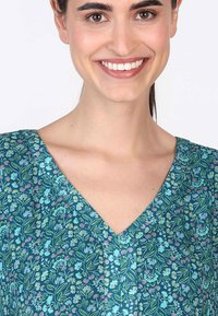 V-Ausschnitt Blumenkleid in Teal mit komplizierten Mustern aus pinken und blauen Blumen, aus einem strukturierten Stoff und mit lockerem Schnitt.