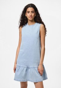 Ljust blå denimklänning utan ärmar med rund halsringning och rynkad nederkant. Har en diskret ficka på sidan. Slät textur.