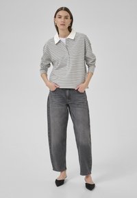 Raido pullover med vit krage, gråa och vita horisontella ränder, i kombination med lösa grå jeans och svarta spetsiga ballerinas. Slät tygtextur.