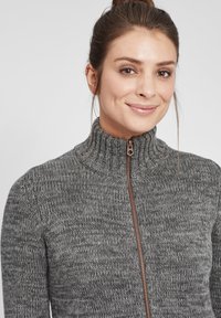 Gray zip-up sweater with a high collar, textured knit pattern, and copper-colored zipper detail. Soft fabric with a relaxed fit.