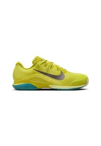 Zapatilla deportiva verde lima con parte superior de malla texturizada, logo Swoosh negro, suela turquesa y puntera reforzada. Cuenta con cordones y cuello acolchado.