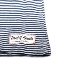 Stribet stof i marineblå og hvid har et rødt syet mærke med teksten "Band of Rascals" og underskrift "Finest Organic Kids Clothes."