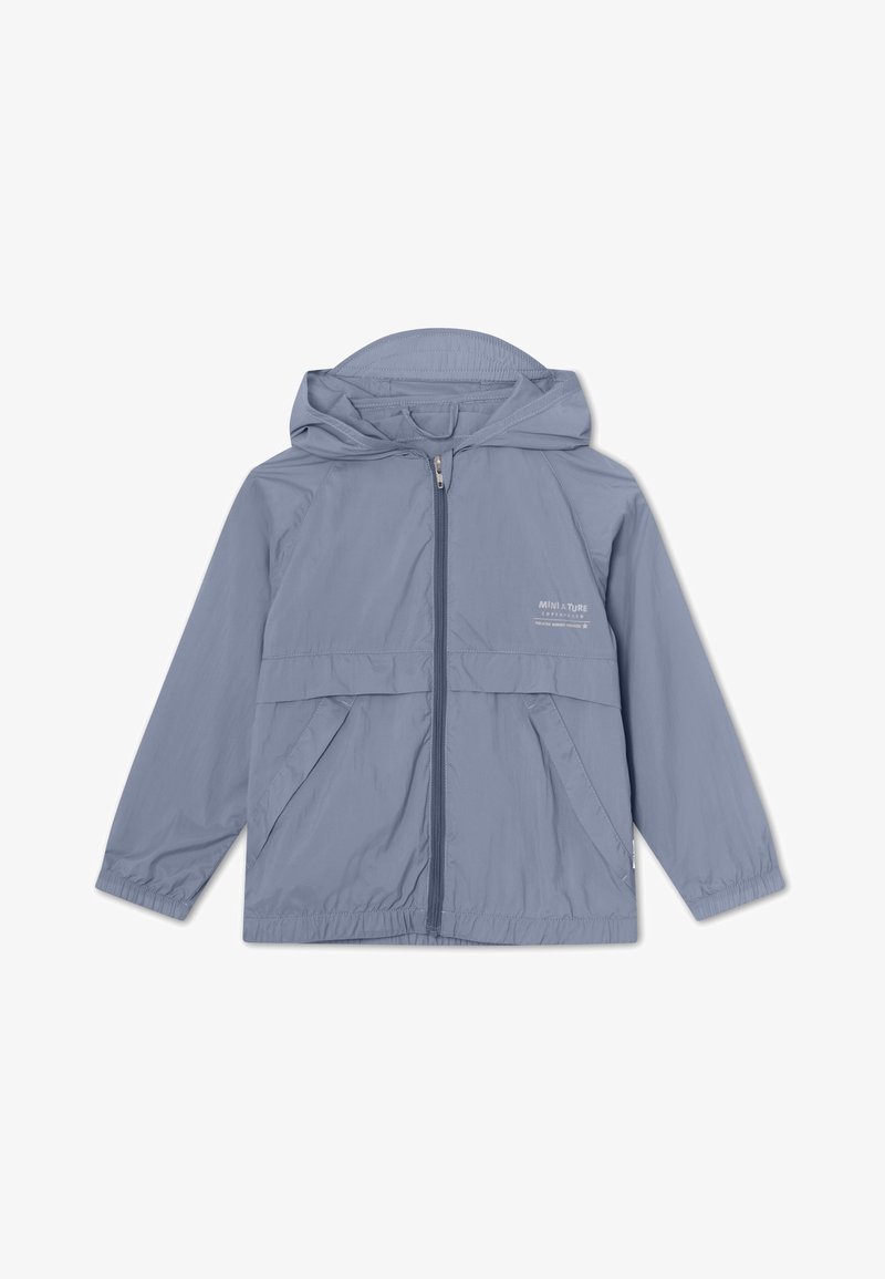 Svjetloplava, lagana jakna protiv vjetra s kapuljačom, prednjim patentnim zatvaračem i dva bočna džepa. Ima elastične manžete i minimalno brendiranje.