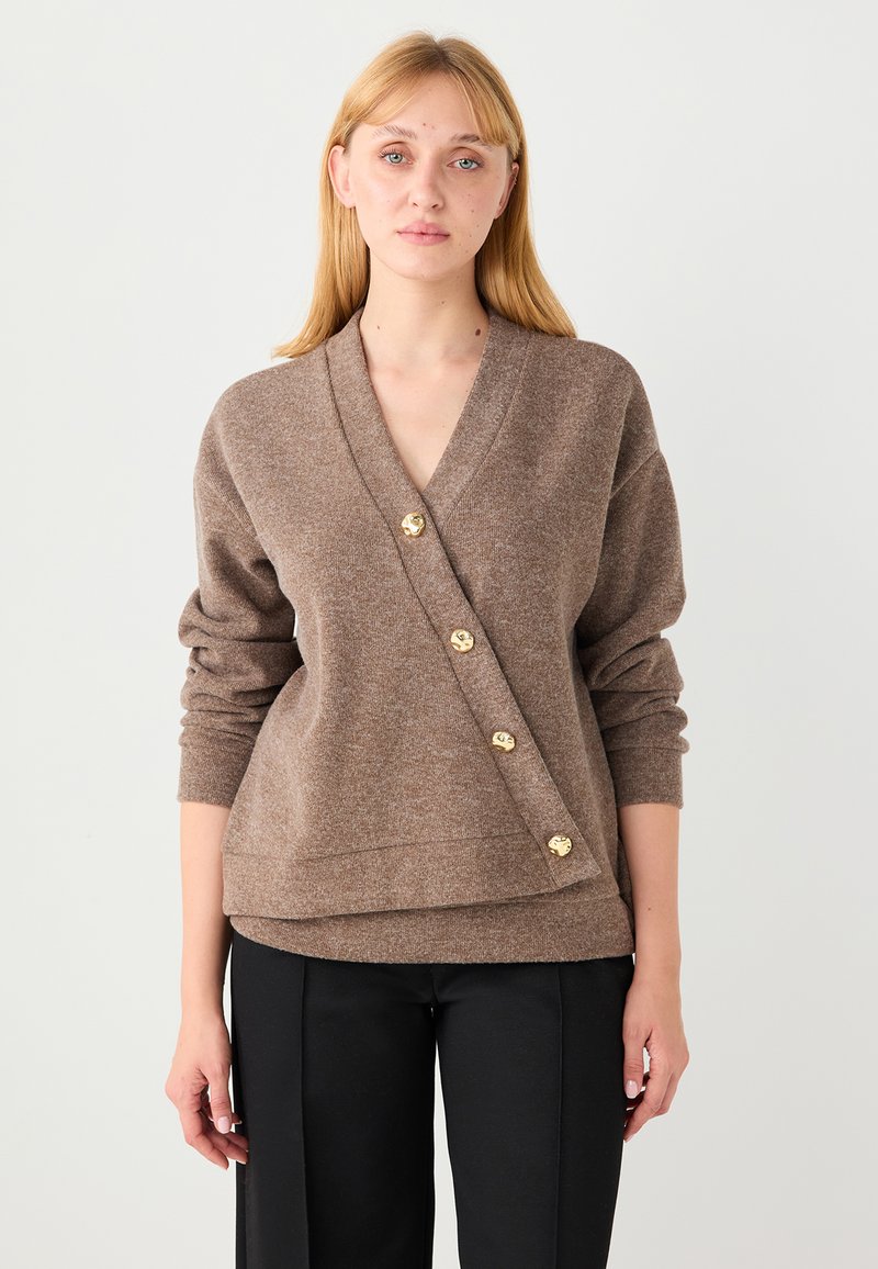 Pull en laine marron avec col en V, manches surdimensionnées et design en portefeuille diagonal. Comprend quatre boutons dorés sur le devant.