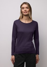 Long-sleeve purple top in a fitted design, made from a soft fabric with a smooth texture and a round neckline.