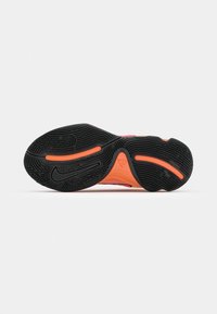 Black sneaker outsole with textured patterns and orange accents. Features a prominent logo and a detailed tread for grip and traction.