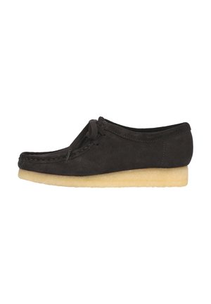 Dark brown suede shoe with a rounded toe, stitched detailing, and a soft yellow rubber sole. Features a lace closure and minimal design.