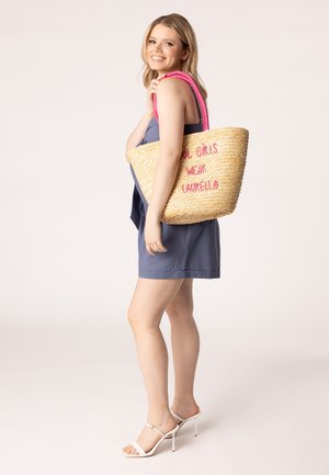 Bolsa de tote de paja tejida con asas rosas y texto bordado "LAS CHICAS REALES LLEVAN LAUREL" en el costado, mostrando una textura natural y un diseño espacioso.