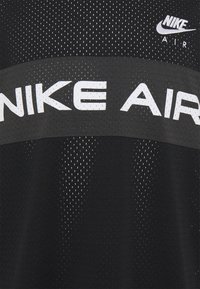 Nike Air svart sporttröja med ett mesh-textur, en framträdande vit "NIKE AIR" logotyp över bröstet och en andningsbar design.