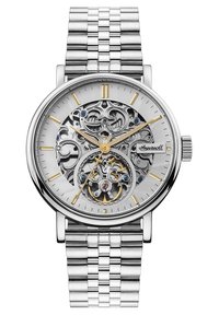 Montre argentée avec un bracelet en acier inoxydable, cadran en métal ouvragé, accents dorés et bleus, et fond texturé argenté.