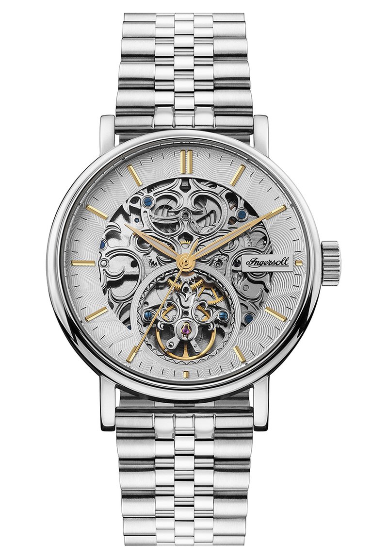 Montre argentée avec un bracelet en acier inoxydable, cadran en métal ouvragé, accents dorés et bleus, et fond texturé argenté.