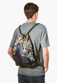 Plecak ze sznurkiem wykonany z tkaniny, z kolorowym wzorem postaci z komiksu, posiada czarne paski oraz wyrazistą, fakturowaną powierzchnię.