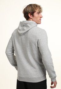 Gray hoodie made of cotton blend. Features a drawstring hood, long sleeves, and ribbed cuffs with a smooth, matte texture.