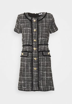 Czarna i biała sukienka z krótkim rękawem wykonana z tkaniny tweed, z złotymi guzikami z przodu i na dwóch przednich kieszeniach, ozdobiona czarnymi lamówkami.