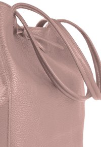 Light pink leather shoulder bag with a textured finish, featuring long, thin handles and a drawstring closure at the top.