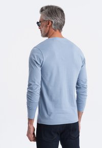 Hellblaues langärmliges T-Shirt aus weicher Baumwolle, mit einem runden Ausschnitt und schmalen Ärmeln, kombiniert mit dunkler Jeans.