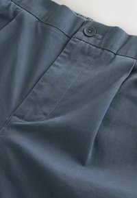 Dunkelblaue Hosen mit glatter Textur, die vordere Falten, einen Bund mit Knopfverschluss und minimale Nähdetails aufweisen.