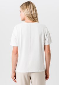 Witte t-shirt met korte mouwen en een eenvoudige snit, met een centrale naad op de rug en een gladde, zachte textuur.