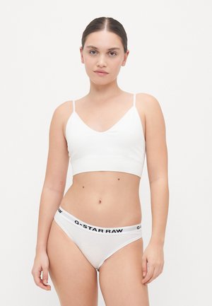 Witte katoenen bralette met dunne banden en een V-hals, gecombineerd met bijpassende witte slipjes met een zwarte logo tailleband. Gladde textuur.