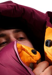 Giacca a vento bordeaux con interno arancione. Include una zip e dettagli in metallo nero, con un tessuto esterno testurizzato.