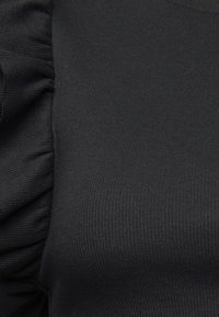 Top di tessuto nero a coste con maniche a sbuffo, caratterizzato da una texture liscia e un design aderente. Articolo semplice e versatile.