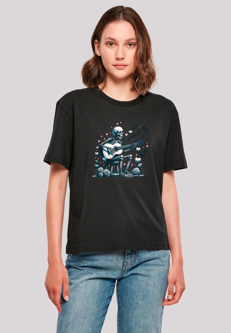Black cotton t-shirt featuring a graphic of a skeleton playing guitar with music notes and hearts, relaxed fit, short sleeves.