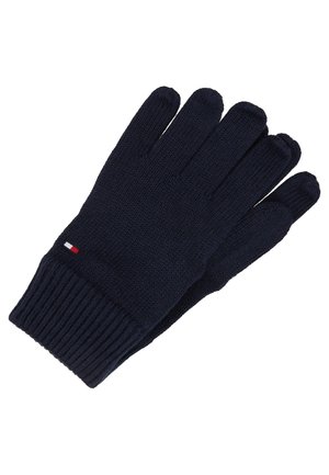 Een paar donkerblauwe gebreide handschoenen met geribde boorden en een klein rood, wit en blauw rechthoekig logo op één handschoen.