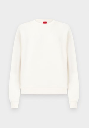 Fehér hosszú ujjú, kerek nyakú pulóver bordázott mandzsettákkal és szegéllyel, a galléron egy kis piros logócímkével.