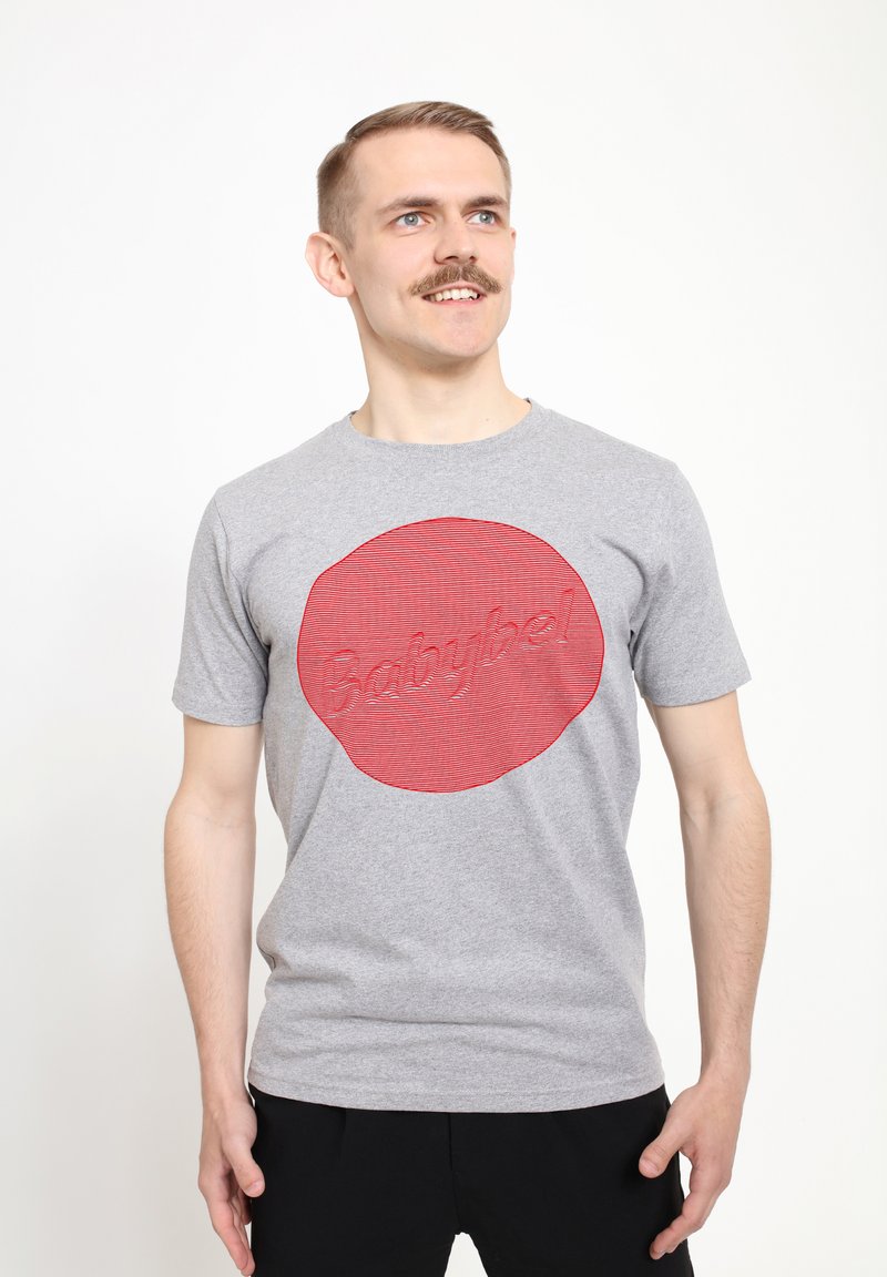 Graues Baumwoll-T-Shirt mit einem großen roten kreisförmigen Design, das strukturierte, gestreifte Effekte aufweist, und dem Wort "Babybel" in erhabenem Schriftzug.