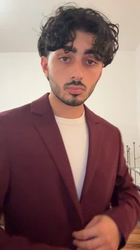 Maroon blazer with notch lapels worn over a white shirt. The fabric appears smooth, and the blazer is partially buttoned.