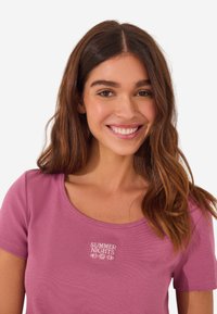 Rosa geripptes T-Shirt mit kurzen Ärmeln und rundem Ausschnitt, das mit weißem, gesticktem Text "SUMMER NIGHTS" in einem floralen Design versehen ist.