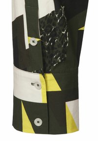 Cotton shirt cuff with geometric patterns in green, black, white, and yellow. Features buttons and contrasting fabric textures.