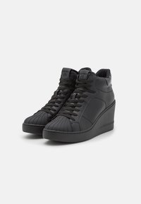 Sneaker alte in pelle nera con punta testurizzata, lacci piatti e tacco a cuneo. Branding sottile sulla linguetta e sul lato.