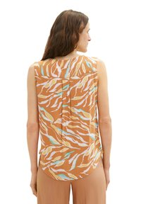 Sleeveless brown top featuring a wavy pattern in cream, yellow, and blue; back pleat detail; rounded hem; lightweight fabric texture.