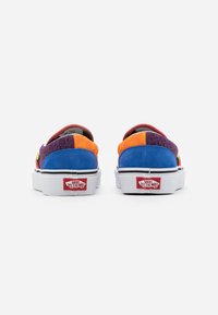Vans slip-on sneakers med en flerfärgad design som har blå, orange, lila och gröna paneler; vita sulor; och signaturlogotypdetalj.
