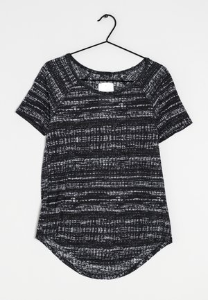 Chemise à manches courtes noire et blanche à motifs avec un col arrondi, présentant un design de rayures texturées et un ourlet arrondi.