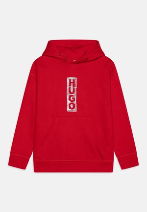 Rød hættetrøje med frontlomme, snøre i hætten og et stort hvidt broderet logo med teksten "HUGO" i et vertikalt design.