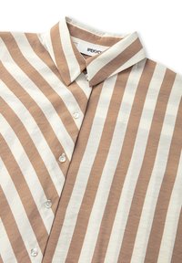 Camicia a righe in beige e crema, con colletto a punta, patta con bottoni e superficie in cotone morbido. Le righe verticali sono distanziate in modo uniforme.