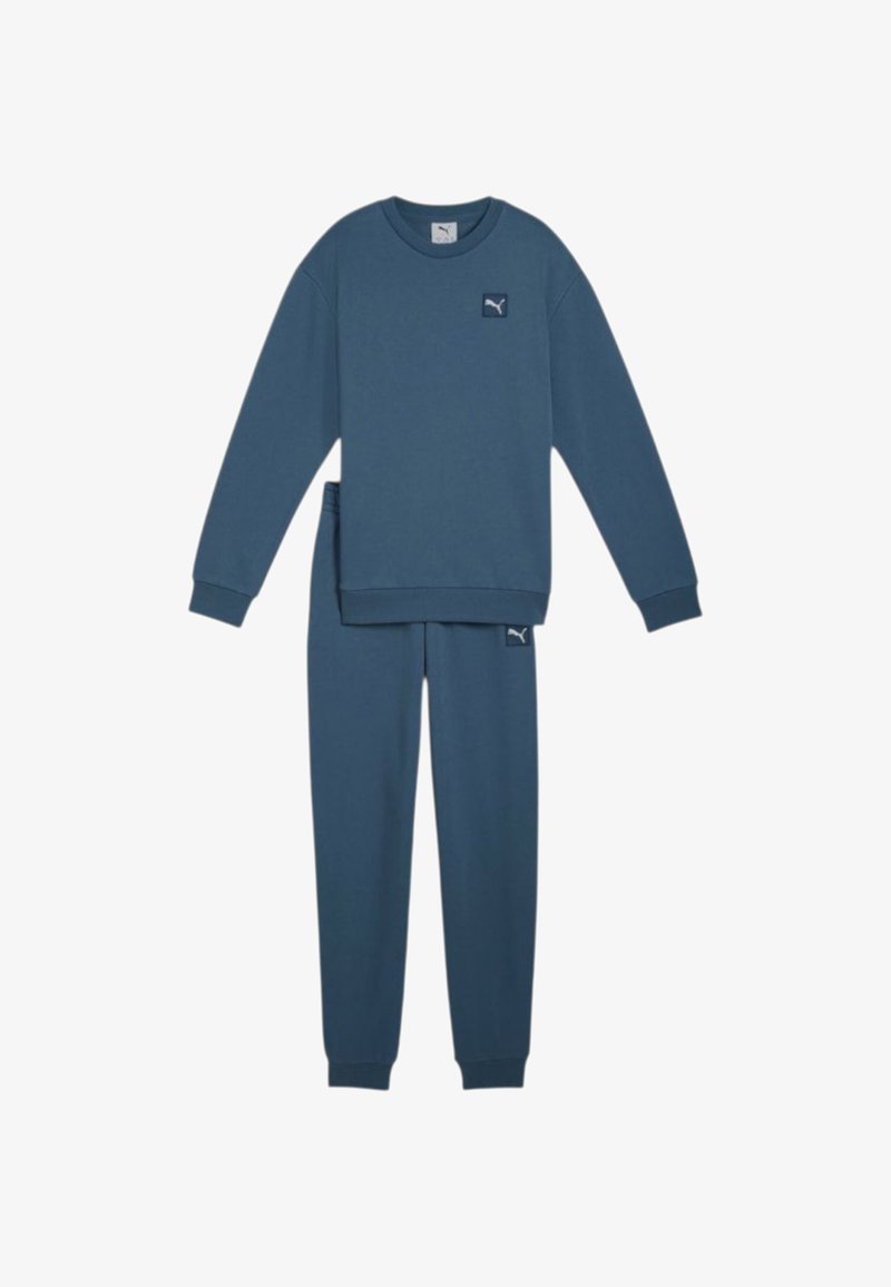 Completo felpa blu composto da felpa e pantaloni in tessuto morbido. Presenta polsini e orlo a costine, con una piccola etichetta logo su entrambi i pezzi.