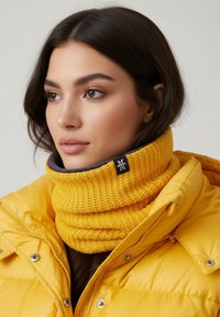 Yellow knitted neck warmer with a ribbed texture, featuring a gray inner lining and a logo tag. Paired with a yellow puffer jacket.