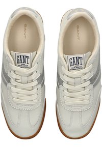 Bílé tenisky s šedými akcenty, hladký kožený svršek, šněrování, polstrovaná podšívka a hnědá gumová podrážka. Logo GANT na jazyku.