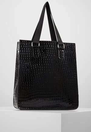 Blank sort tote taske med krokodilleskindstruktur og dobbelte flade håndtag, vist på en hvid piedestal mod en grå baggrund.