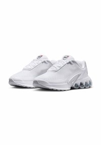 Zapatillas deportivas blancas con parte superior de malla, cordones redondos y suela acolchada que presenta un diseño en capas distintivo y unidades de aire visibles en el talón.