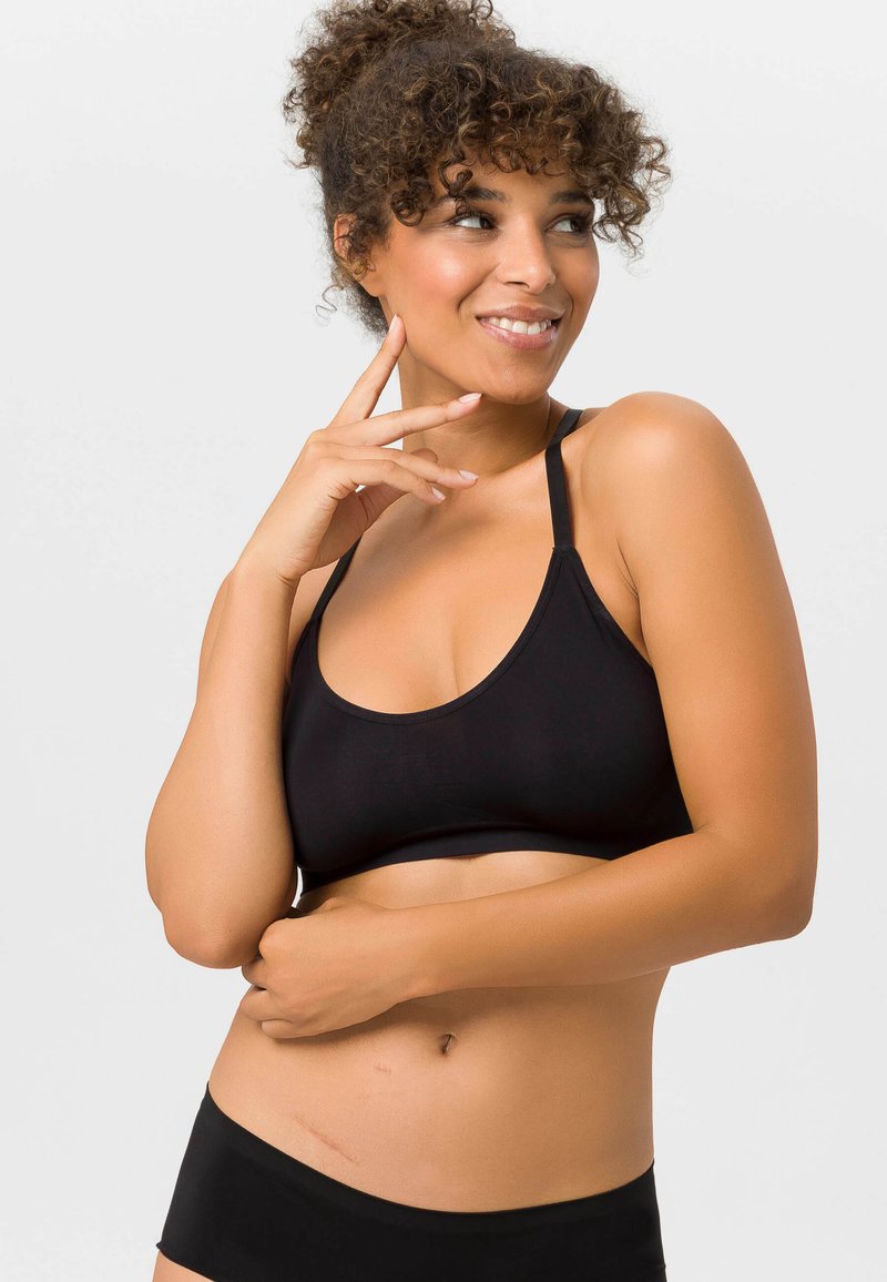 Schwarzer Sport-BH aus glattem Material, mit rundem Ausschnitt und dünnen, verstellbaren Trägern, kombiniert mit passenden schwarzen Shorts.