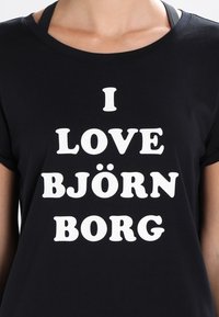Camiseta negra de manga corta con texto blanco en negrita que dice "ME ENCANTA BJÖRN BORG". Corte casual con cuello redondo.