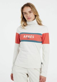 Weißes Langarm-Turtleneck mit roten und tealfarbenen horizontalen Streifen. Die Vorderseite zeigt den Text "APRÈS Ski" in fetter Schrift. Weiche Stofftextur.