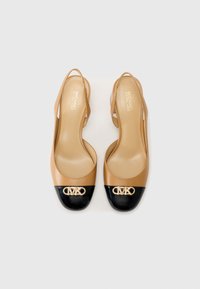 Scarpe slingback in pelle beige con punta a cappuccio nera lucida, caratterizzate da un'accenno del logo in tonalità dorata. Texture liscia con design aperto sul retro.
