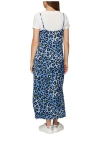 Blauwe luipaardprint maxi jurk met verstelbare banden, met een losse fit en zijsplitten, gecombineerd met witte sneakers.