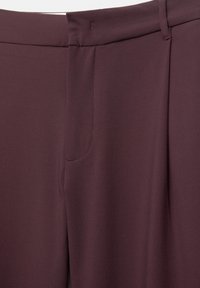 Pantalon ajusté en grenat foncé avec un devant lisse, une ceinture et un détail de couture latérale en gros plan.