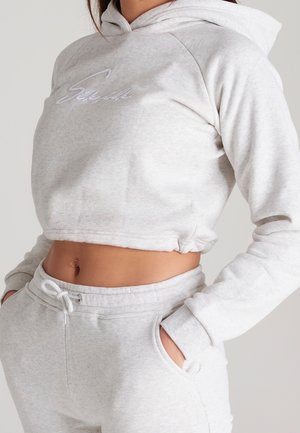 Felpa corta color grigio chiaro con cappuccio e coulisse, con logo ricamato. Tessuto morbido, polsini a coste e pantaloni jogger coordinati con tasche.